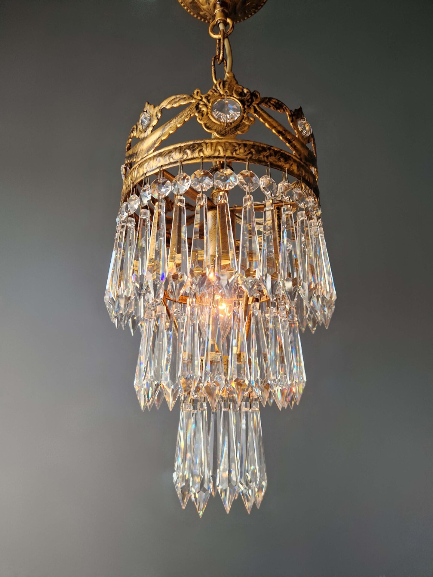 messingornament und kristallteile einer kleinen deckenleuchte antik